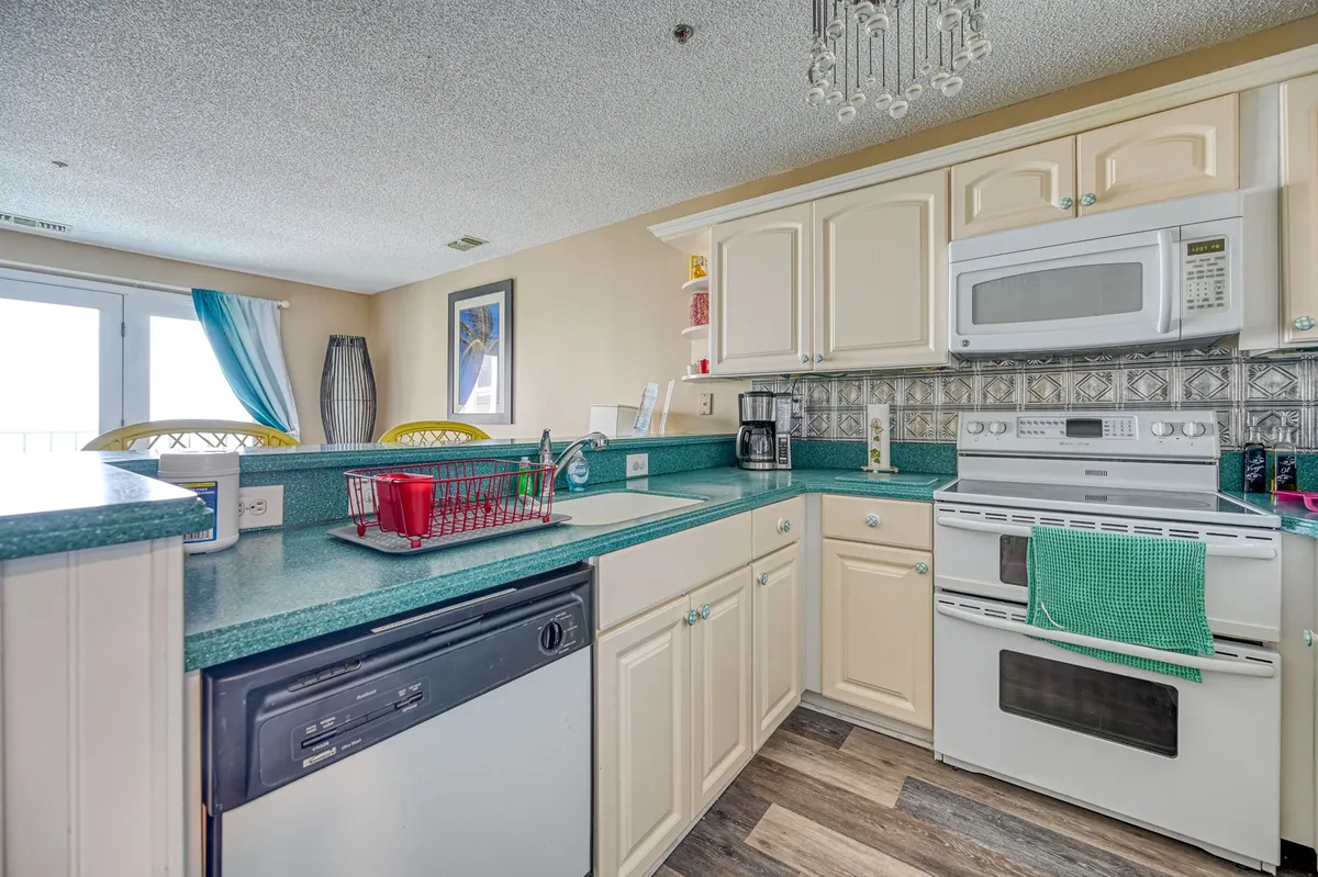 A bright, cheerful kitchen scene with a spacious countertop, modern appliances, and a curtained window. The atmosphere is relaxed and inviting, ideal for preparing meals, entertaining guests, or gathering for family celebrations.