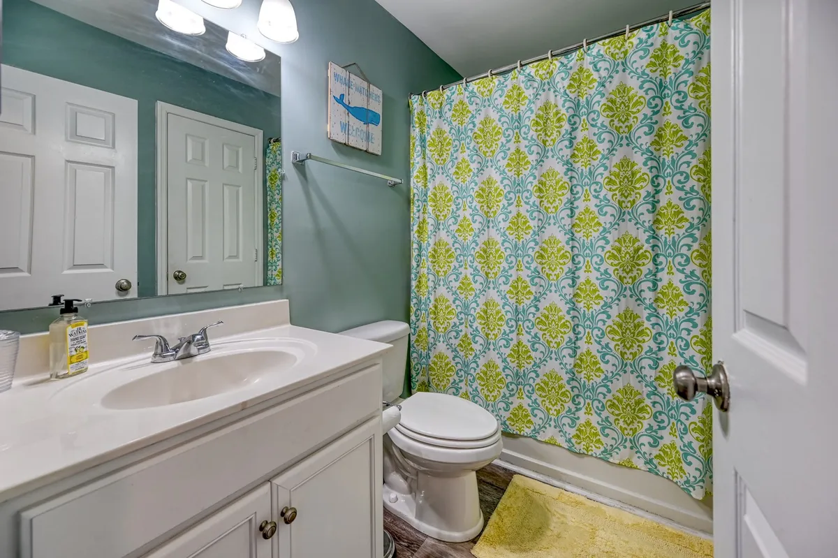A modern ensuite bathroom featuring a bright, lively color palette, a stylish vanity, and a colorful shower curtain. The setup suggests both comfort and privacy, making it a pleasant space for personal routines and relaxation.