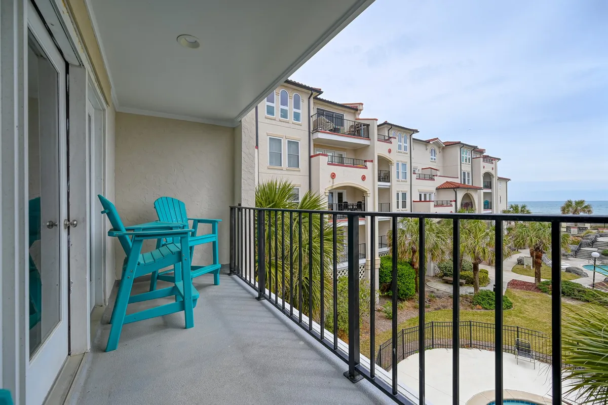The image shows a private condo balcony with a turquoise chair positioned to take in unobstructed, breathtaking ocean views. The balcony overlooks endless blue waves and hints at the soothing coastal breeze, with sunlight sparkling on the water, and an inviting, relaxed atmosphere for morning coffee or evening drinks.