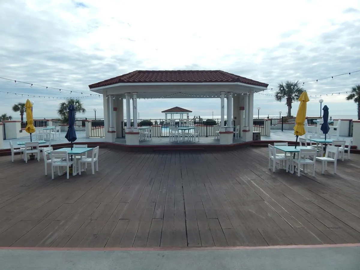 A picturesque exterior setting with a gazebo, outdoor seating, palm trees, and a view of the ocean. This inviting scene could host family meals, group gatherings, or quiet moments, all in a breezy, tropical environment.