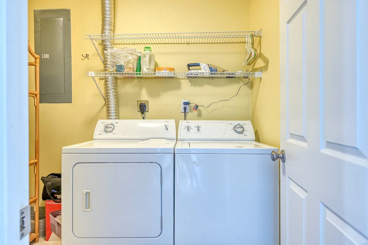 This image features a convenient laundry area with a washing machine, dryer, and organized shelves stocked with cleaning supplies. The setup is clean, orderly, and clearly intended for guest use, emphasizing practical aspects of an extended stay.